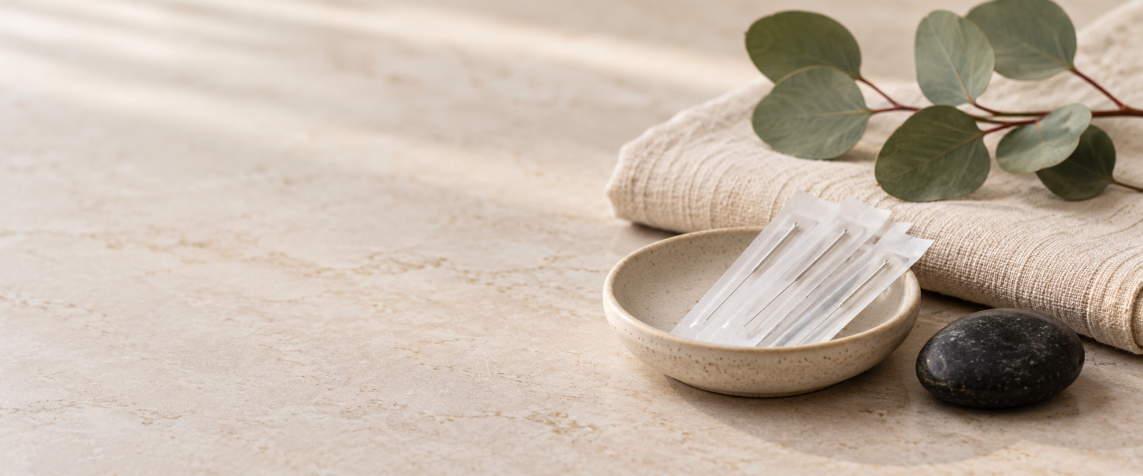 Sterile packaged acupuncture needles arranged with linen and eucalyptus